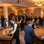 Corporate event transformed into a vibrant "fake casino" with guests playing blackjack and roulette in a warm, lively setting.